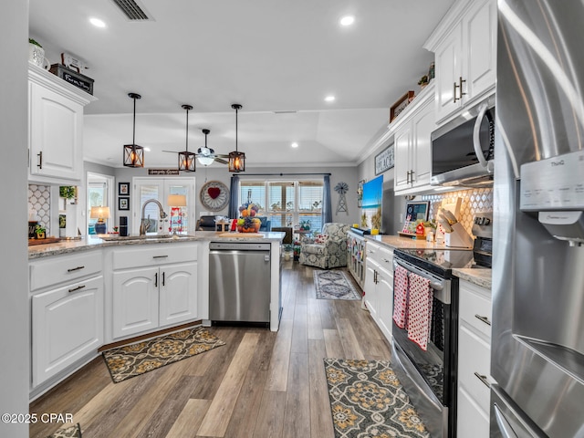 kitchen with tasteful backsplash, hardwood / wood-style floors, appliances with stainless steel finishes, a peninsula, and a sink