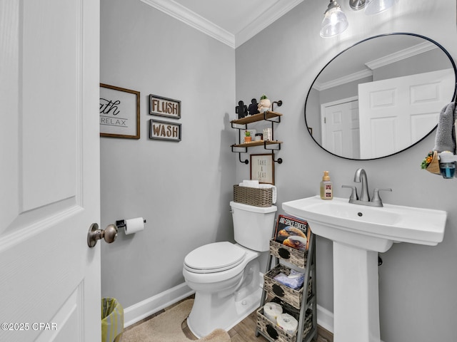 bathroom featuring crown molding, toilet, and baseboards