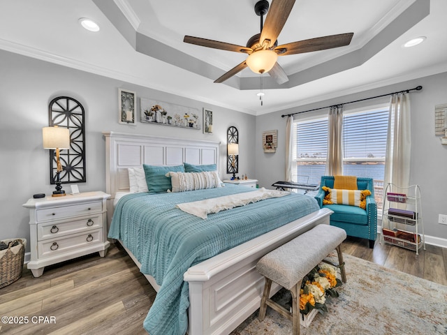 bedroom with a raised ceiling, light wood-style flooring, baseboards, and ornamental molding