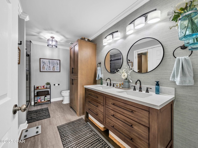 bathroom with a sink, toilet, double vanity, and crown molding