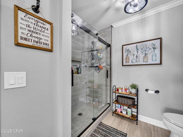 bathroom featuring a shower stall, toilet, crown molding, and baseboards