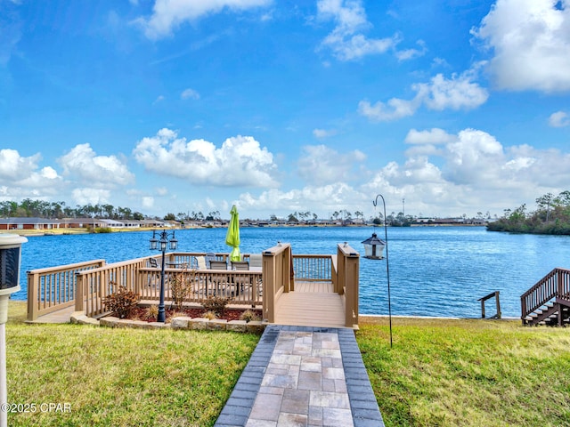 view of dock with a yard and a water view