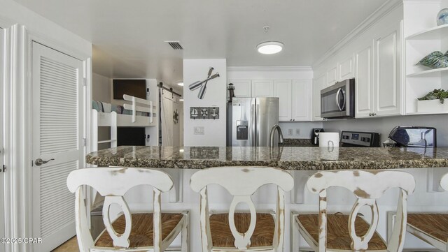 9450 S Thomas Unit 2106D, Panama City, FL 32408 - kitchen featuring stainless steel appliances, open shelves, a peninsula, a kitchen bar, and white cabinetry