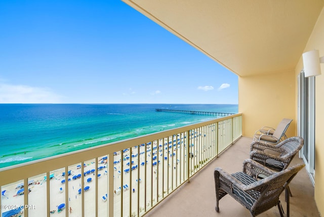 balcony featuring a view of the beach and a water view