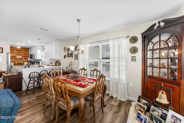 dining space with visible vents, baseboards, an inviting chandelier, and wood finished floors