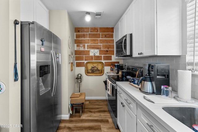 kitchen featuring backsplash, white cabinets, stainless steel appliances, and light countertops