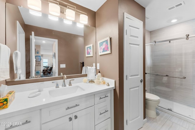 full bath featuring visible vents, vanity, a shower stall, and toilet