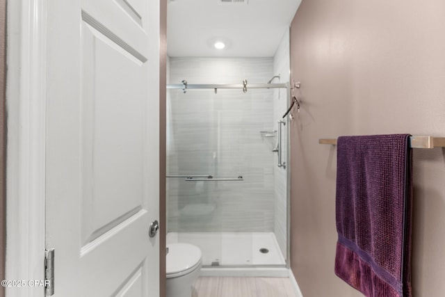 bathroom featuring a shower stall, toilet, and visible vents