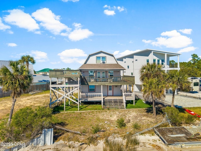 rear view of house with a deck, a fenced backyard, and a lawn