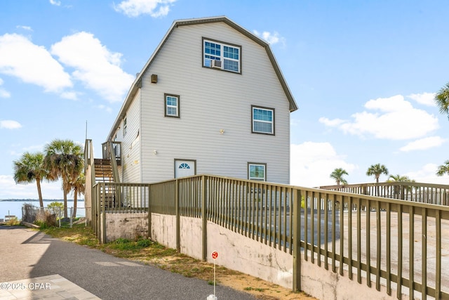 view of side of property with stairway, a water view, and a gambrel roof