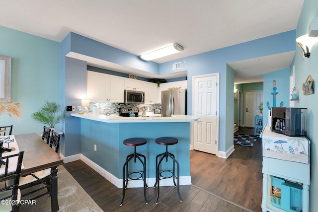 kitchen featuring a peninsula, dark wood-style floors, tasteful backsplash, and stainless steel appliances