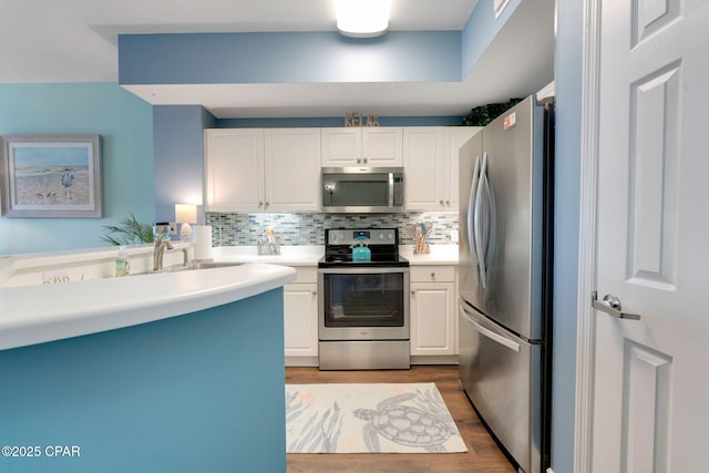 kitchen with wood finished floors, tasteful backsplash, appliances with stainless steel finishes, and white cabinets