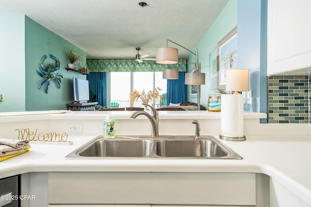 kitchen with ceiling fan, a sink, light countertops, a textured ceiling, and white cabinetry