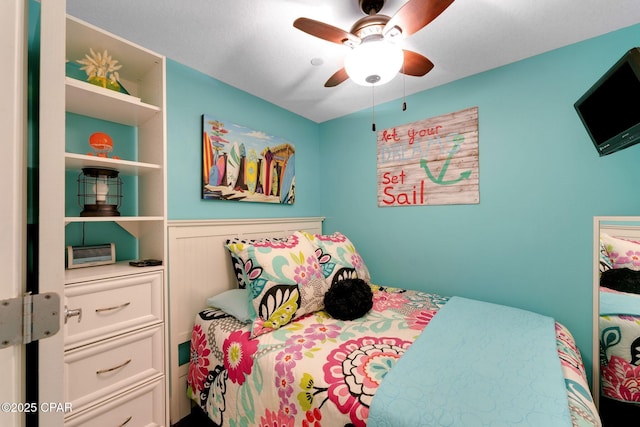 bedroom with a ceiling fan and wainscoting