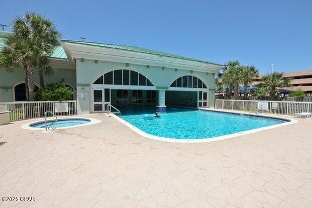 pool featuring a patio area, fence, and a hot tub