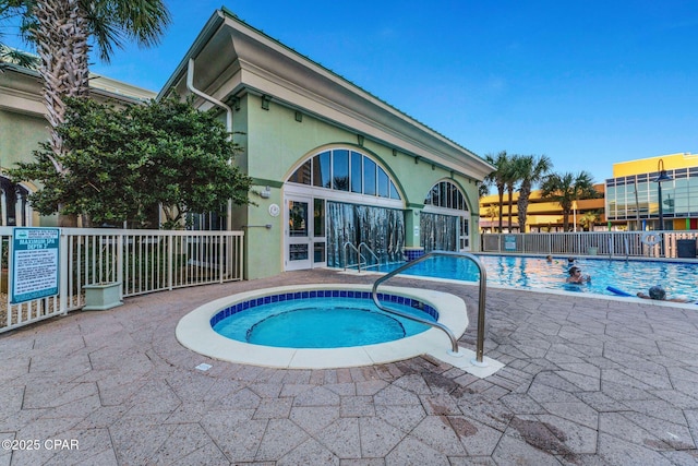 pool featuring fence and a hot tub