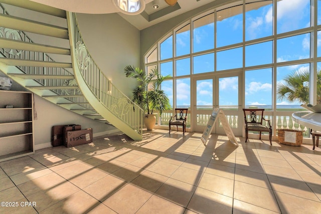 unfurnished living room featuring baseboards, a towering ceiling, stairs, and tile patterned flooring