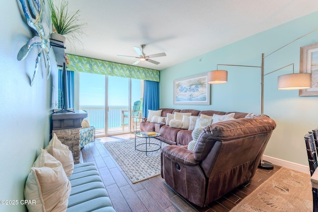 living area with baseboards, a water view, wood finished floors, and a ceiling fan