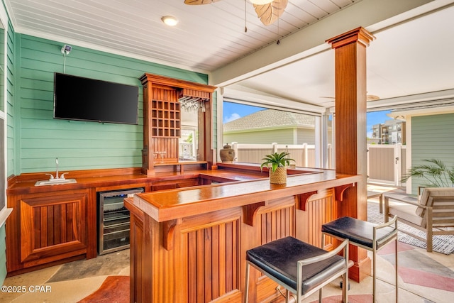 bar featuring a ceiling fan, wet bar, decorative columns, a sink, and wine cooler