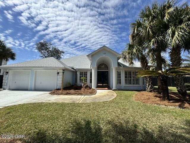 view of front facade featuring a front lawn, a garage, driveway, and stucco siding