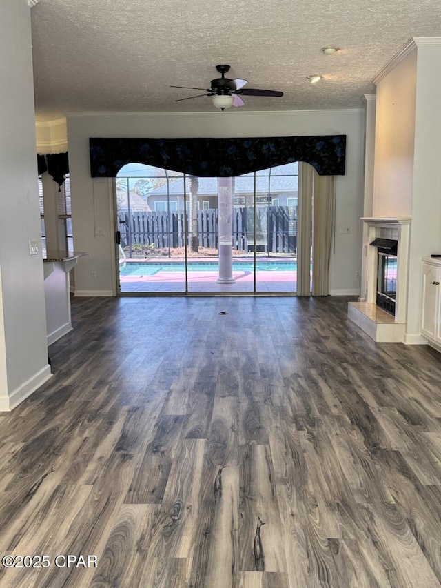 unfurnished living room featuring a fireplace, crown molding, wood finished floors, and a wealth of natural light