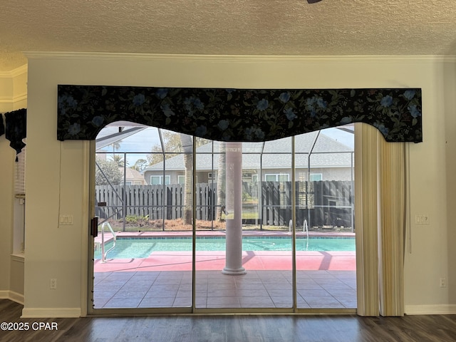 doorway to outside featuring a wealth of natural light, ornamental molding, a textured ceiling, and wood finished floors