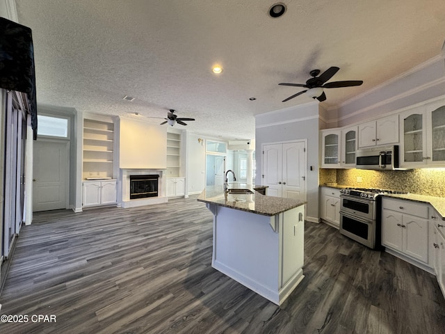 kitchen featuring stainless steel microwave, range with two ovens, a glass covered fireplace, a textured ceiling, and a sink