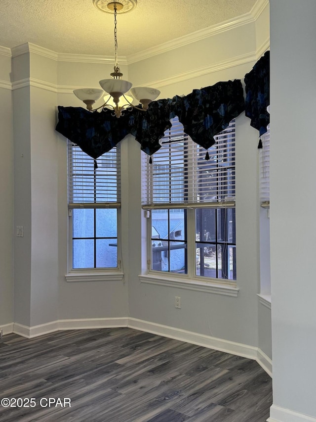 unfurnished dining area with wood finished floors, baseboards, an inviting chandelier, ornamental molding, and a textured ceiling