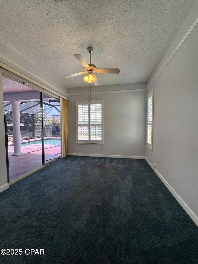 spare room with a sunroom, baseboards, dark carpet, and ceiling fan