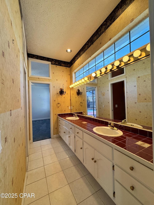 bathroom featuring double vanity, tile patterned floors, a textured ceiling, and a sink