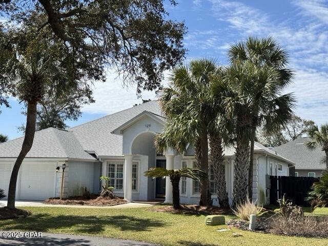 view of front of home featuring stucco siding, a front yard, a garage, and a shingled roof