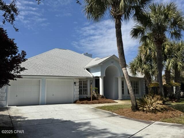 view of front facade with roof with shingles, a garage, driveway, and stucco siding