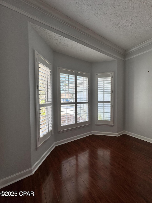 empty room with baseboards, a textured ceiling, dark wood finished floors, and crown molding