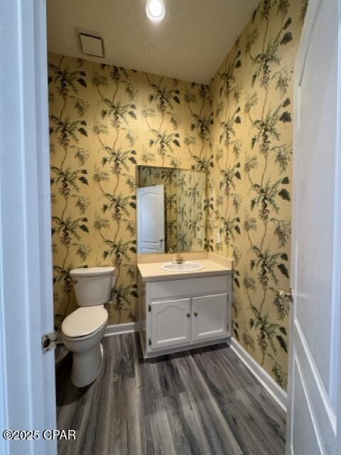 bathroom with baseboards, toilet, vanity, and wallpapered walls