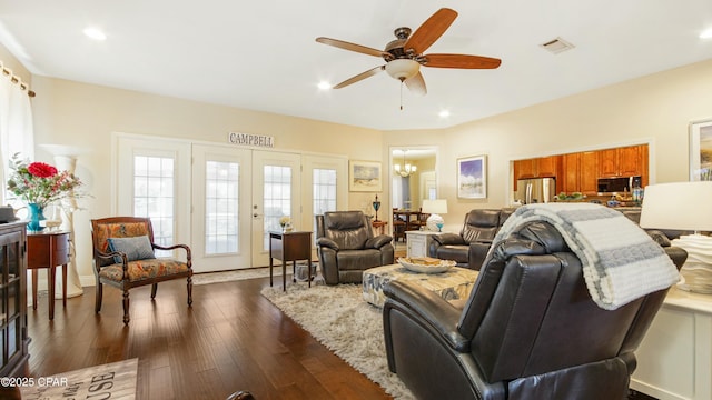 living room featuring recessed lighting, ceiling fan with notable chandelier, visible vents, and dark wood-style flooring