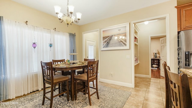 dining space featuring baseboards, an inviting chandelier, and light tile patterned flooring