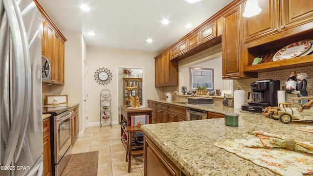 kitchen with light stone counters, stainless steel appliances, and brown cabinetry