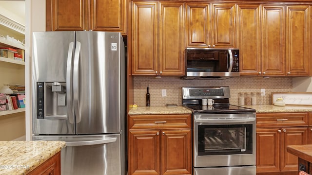 kitchen featuring brown cabinetry, tasteful backsplash, light stone countertops, and stainless steel appliances