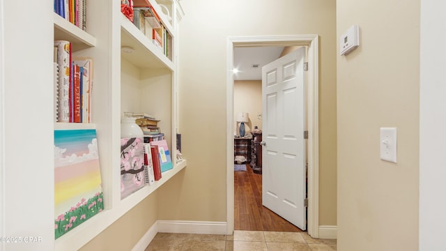 hall featuring light tile patterned flooring and baseboards