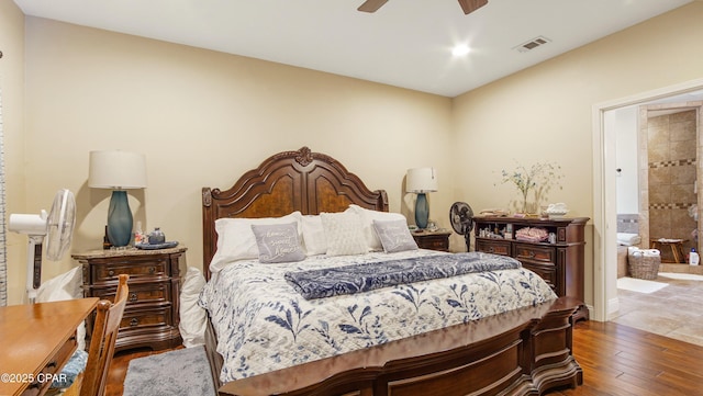 bedroom with visible vents, ensuite bath, a ceiling fan, and wood finished floors