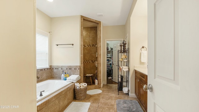 bathroom featuring a spacious closet, a garden tub, tiled shower, tile patterned floors, and vanity