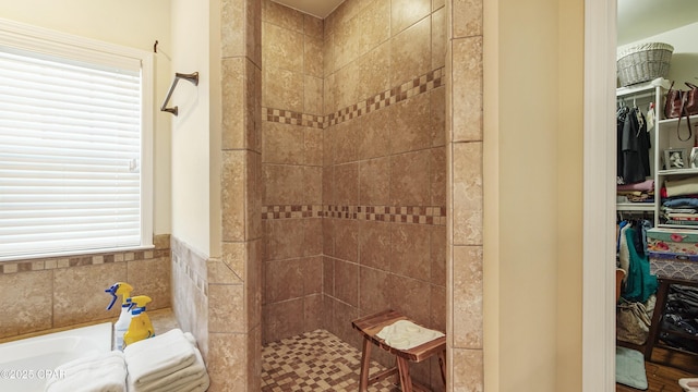 full bathroom featuring a garden tub, a spacious closet, and a tile shower