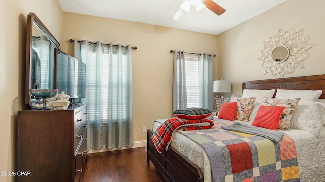 bedroom with dark wood-type flooring, a ceiling fan, and baseboards