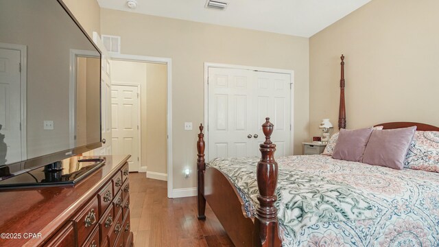 bedroom with dark wood-style floors, visible vents, and baseboards