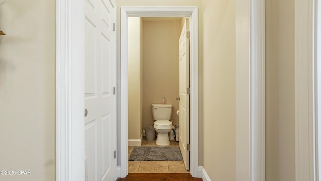 hallway featuring baseboards and dark tile patterned flooring