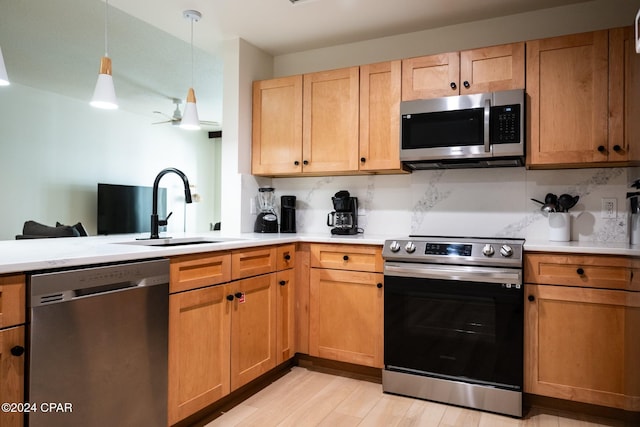 kitchen with backsplash, light wood finished floors, stainless steel appliances, and a sink