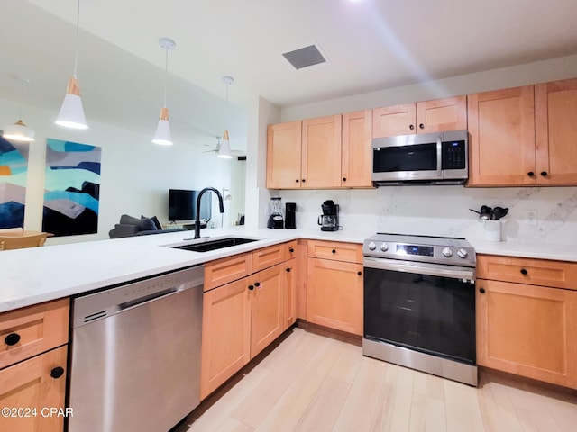 kitchen with stainless steel appliances, light brown cabinets, light countertops, and a sink