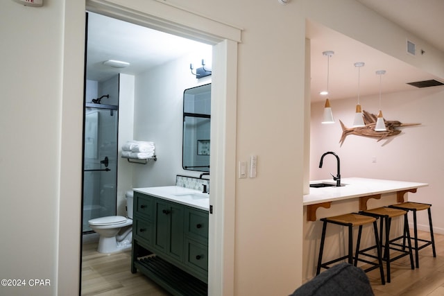full bathroom featuring wood finished floors, vanity, a shower with door, and toilet