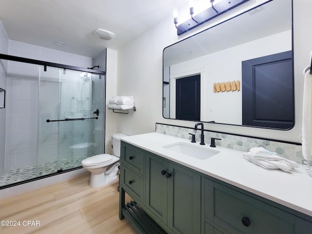 full bathroom with a shower stall, wood finished floors, toilet, and vanity
