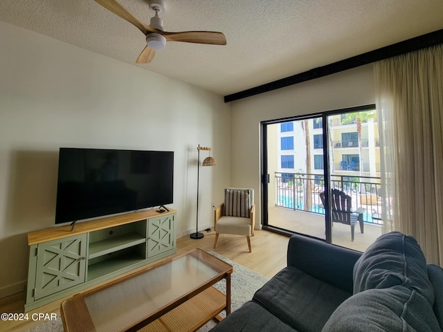 living room with light wood-style flooring, a textured ceiling, baseboards, and ceiling fan